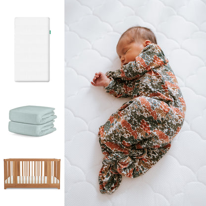 A baby sleeps in a floral swaddle on Newton Baby’s Nest Convertible Crib with the Original Mattress and a light blue organic cotton sheet, shown alongside product images. 111-8420-CST-1000-WHT-SNS
