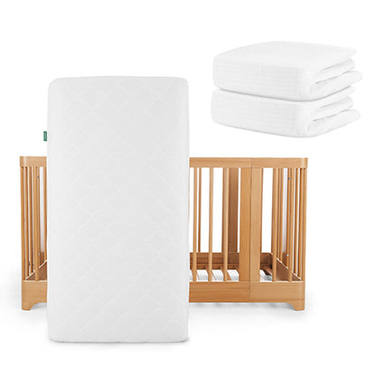 A Newton Baby Nest Convertible Crib with Original Mattress stands upright, with two folded sheets stacked nearby.
