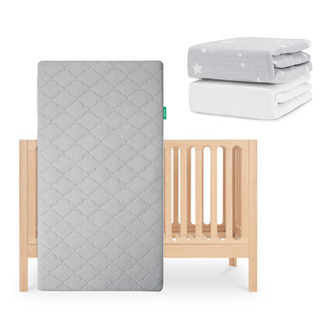 The Newton Baby Galileo Crib stands upright with the Original Crib Mattress (gray-patterned, breathable). Two folded sheets—one gray with white stars and one organic cotton—are placed above and to the right of the crib. skip