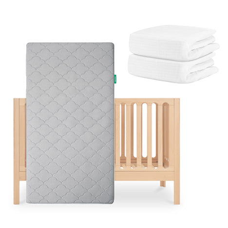 The Newton Baby Galileo Crib stands upright with the Original Crib Mattress, featuring a breathable grey pattern, in front, while two folded organic cotton sheets are displayed in the top right corner. skip