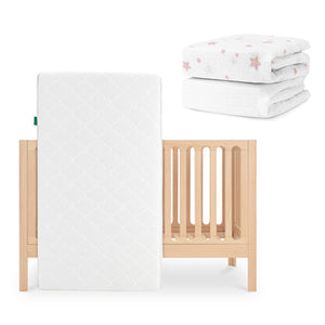 The Newton Baby Galileo Crib in light wood with the Original Crib Mattress is pictured, alongside a folded stack of organic cotton sheets featuring a pink star pattern. skip