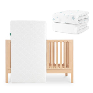 The Galileo Crib by Newton Baby with the Original Crib Mattress stands upright, while two folded Newton Baby sheets—one white with blue stars, one plain white—are stacked together in the background. skip