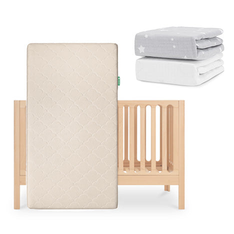 The Newton Baby Galileo Crib stands upright with the Original Crib Mattress in beige, plus two folded sheets: one gray with white stars and one plain organic cotton—all from the Newton Baby Galileo Crib, Original Mattress & Sheets set. skip