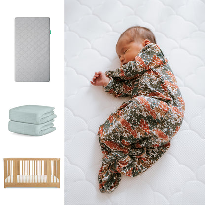 A baby in a floral sleep sack sleeps on the Newton Baby Nest Convertible Crib with the Original Mattress and pale blue Breathable Organic Cotton Sheet, shown vertically as product options. 111-8420-NAT-1000-GRY-SNS
