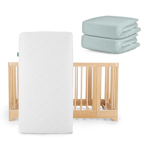 The Newton Baby Nest Convertible Crib, Original Mattress, and mint green fitted sheets from the Nest Sleep Bundle are neatly arranged together.