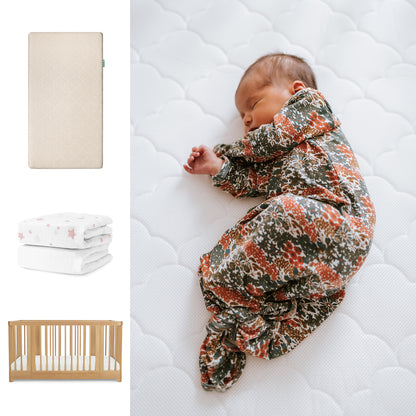 A newborn in a floral swaddle sleeps on Newton Baby’s Nest Convertible Crib with the Original Mattress and breathable organic cotton sheets. Nearby are folded star-print blankets, with images of the crib and bedding on the left. 111-8420-NAT-1000-SAN-PSW