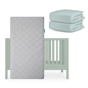 The Newton Baby Galileo Crib in light green is shown with the Original Crib Mattress propped upright in front and two folded light green organic cotton sheets stacked beside it. skip
