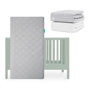 The Newton Baby Galileo Crib is shown with the Original Crib Mattress standing upright. Two sheets—a gray with white stars and a solid organic cotton—are folded nearby. skip