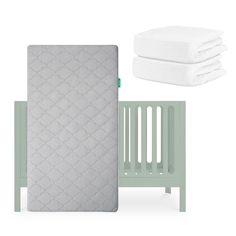 A light gray Newton Baby Galileo Crib with an Original Crib Mattress stands upright, while two folded Breathable Organic Cotton Sheets are stacked in the upper right corner. skip