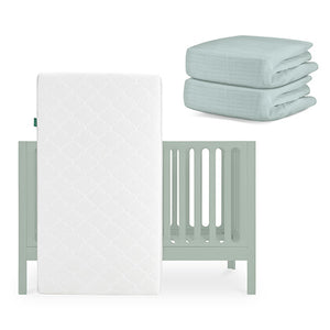 A Newton Baby Galileo Crib with an Original Crib Mattress leans against it, and two folded Breathable Organic Cotton Sheets are stacked nearby. skip