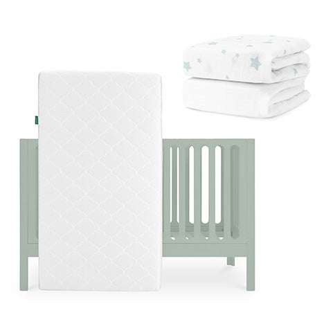 A light green Newton Baby Galileo Crib with an Original Crib Mattress leans nearby. Two white crib sheets with blue stars, including a breathable organic cotton sheet, are placed above and to the right of the crib. skip