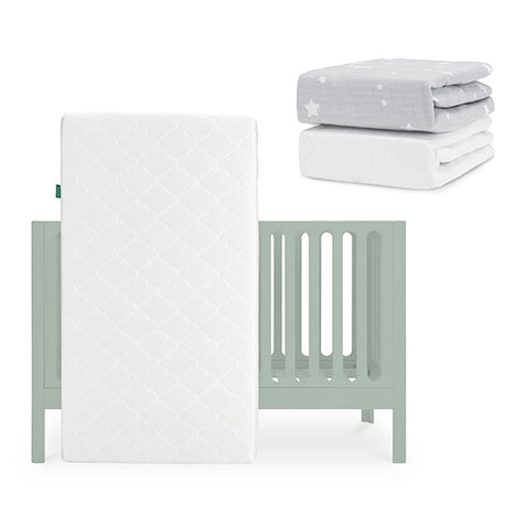 The Newton Baby Galileo Crib, Original Crib Mattress & Sheets set is shown in light green. Two folded fitted sheets—one gray with white stars, the other a solid white Breathable Organic Cotton Sheet—are stacked above the crib. skip