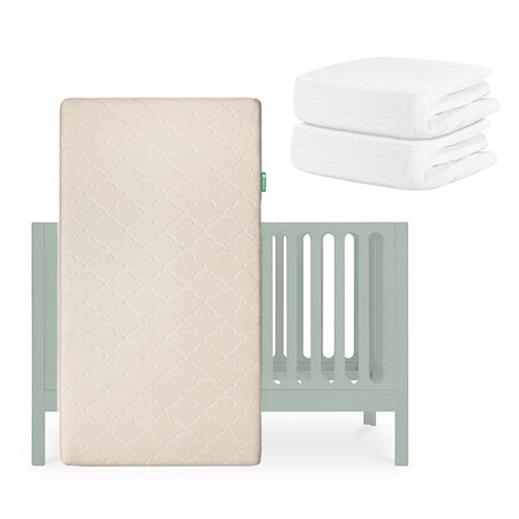 A light green Newton Baby Galileo Crib with the Original Crib Mattress upright in front and two folded white Breathable Organic Cotton Sheets beside it, all against a white background. skip