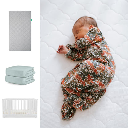 A baby in a floral sleeper rests on the Newton Baby Nest Convertible Crib with the Original Mattress and Breathable Organic Cotton Sheets. To the left are images of the crib, mattress, and folded sheet. 111-8420-WHT-1000-GRY-SNS
