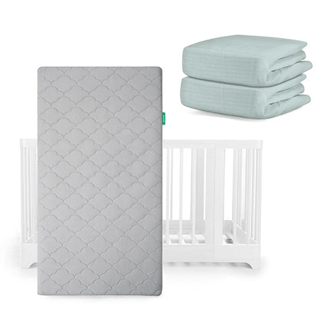 A Newton Baby Nest Convertible Crib and Original Mattress are shown with two folded blue breathable organic cotton sheets placed above and to the right.
