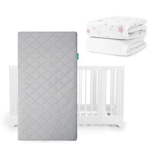 A gray Newton Baby Original Mattress stands upright before a white Nest Convertible Crib, with folded Breathable Organic Cotton Sheets—one with pink stars, one white—stacked above and to the right.