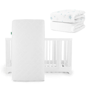 A white Newton Baby Original Mattress stands vertically before a Nest Convertible Crib, with breathable organic cotton sheets featuring light blue stars folded in the background.