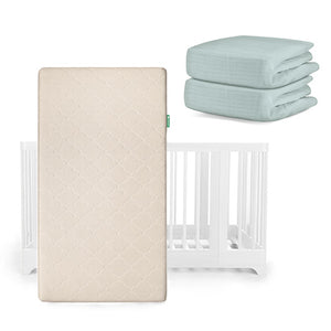 A Nest Convertible Crib by Newton Baby with the Original Mattress in beige in front, plus two folded light blue Breathable Organic Cotton Sheets stacked beside it.