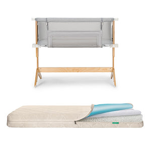 The Newton Baby Bassinet & Bedside Sleeper is shown with gray fabric sides above a breathable, waterproof mattress featuring a zippered cover partially open to reveal its blue and white inner layers.