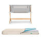 The Newton Baby Bassinet & Bedside Sleeper is shown with gray fabric sides above a breathable, waterproof mattress featuring a zippered cover partially open to reveal its blue and white inner layers.