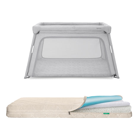 The Newton Baby Deluxe Travel Crib + Waterproof Crib Mattress is shown in light gray with mesh sides, its beige top unzipped to reveal the washable mattress and inner cushioning materials.