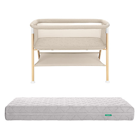 The Essential Bassinet + Original Crib Mattress by Newton Baby features a beige bedside design with wooden legs, a convenient storage shelf, and comes with a separate quilted gray breathable mattress.