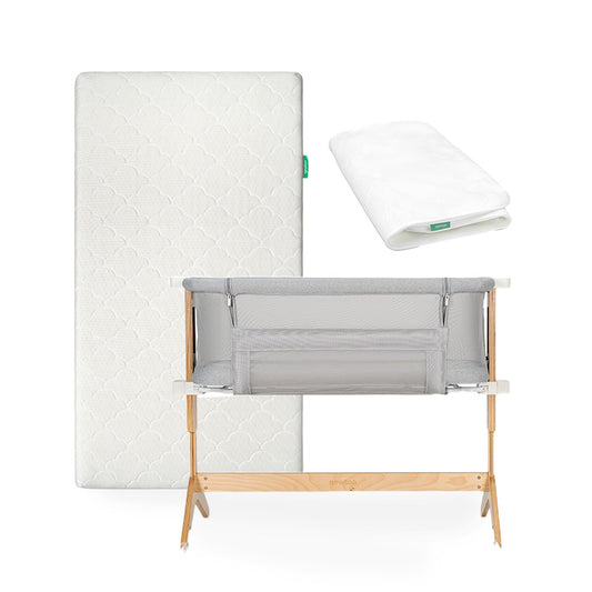 The Newton Baby Bundle 6 BFCM features a baby bassinet with a wooden frame and grey mesh sides, displayed in front of a white mattress and a folded white mattress protector, all set against a white background.