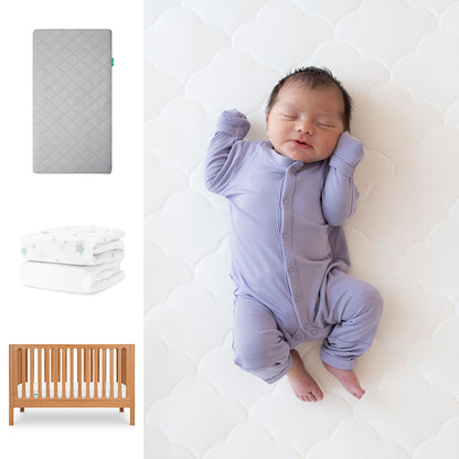 A newborn in a lavender onesie sleeps on Newton Baby’s Galileo Crib with the Original Crib Mattress and star-patterned Organic Cotton Sheets. Images also show the gray crib mattress and wooden Galileo Crib. 111-8420-CST-1000-GRY-SDW
