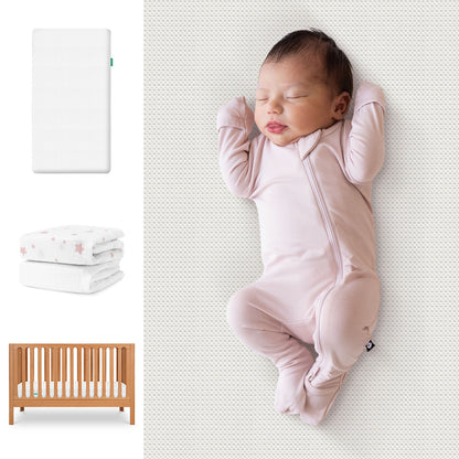 A newborn in a pale pink onesie sleeps on a patterned surface beside images of the Newton Baby Galileo Crib, Essential Crib Mattress, and Sheets Bundle. 111-8420-CST-1300-WHT- PSW