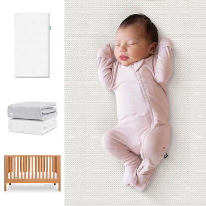 A baby in a light pink onesie sleeps on a Newton Baby Essential Crib Mattress. To the left are images of the Galileo Crib, folded gray and white sheets, and the Essential Crib Mattress—all part of the Newton Baby Sheets Bundle. 111-8420-CST-1300-WHT- SGW