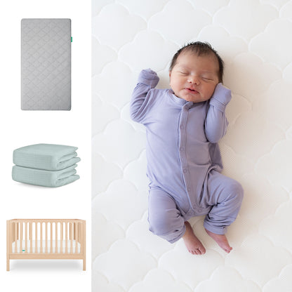A baby in a lavender onesie sleeps on the Newton Baby Galileo Crib, Original Crib Mattress & Sheets. Nearby are images of the gray Galileo 3-in-1 Convertible Crib, two folded organic cotton sheets, and a wooden crib. 111-8420-NAT-1000-GRY-SNS
