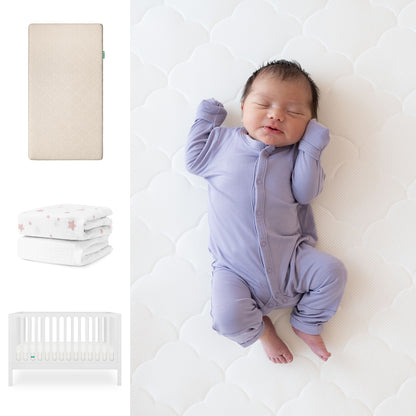 A baby sleeps on the Newton Baby Galileo Crib with the Original Crib Mattress and Sheets. To the left are images of the convertible crib, two folded patterned blankets, and an organic cotton sheet. 111-8420-WHT-1000-SAN-PSW

