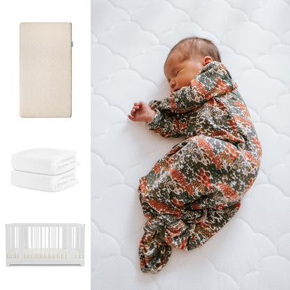 A baby sleeps in a floral onesie on Newton Baby's Nest Convertible Crib with the Original Mattress and breathable organic cotton sheets. On the left are images of the crib, mattress, and folded white sheets. 111-8420-WHT-1000-SAN-WNW