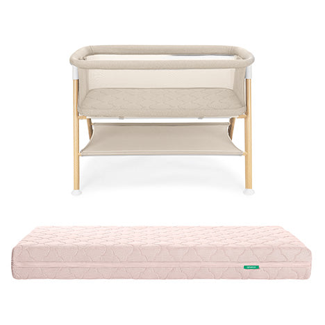 The Newton Baby Essential Bassinet with light wood legs and a lower storage shelf is displayed behind the Original Crib Mattress, both shown against a white background.