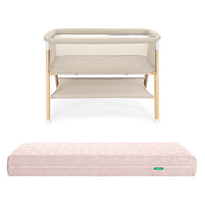 The Newton Baby Essential Bassinet with light wood legs and a lower storage shelf is displayed behind the Original Crib Mattress, both shown against a white background.
