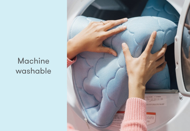 Hands placing a blue, breathable baby mattress into a washing machine, with the text "Machine washable" displayed.