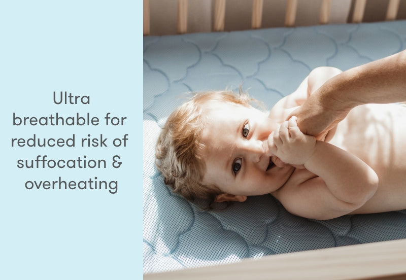 ALT text: "Baby lying on a blue, breathable crib mattress, interacting playfully with an adult hand, accompanied by text: 'Ultra breathable for reduced risk of suffocation & overheating'."