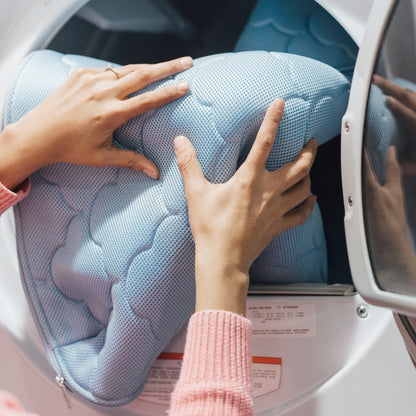hands placing mattress cover in washing machine