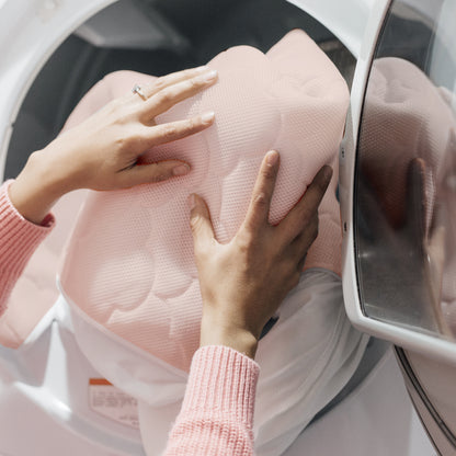hands placing mattress cover in washing machine