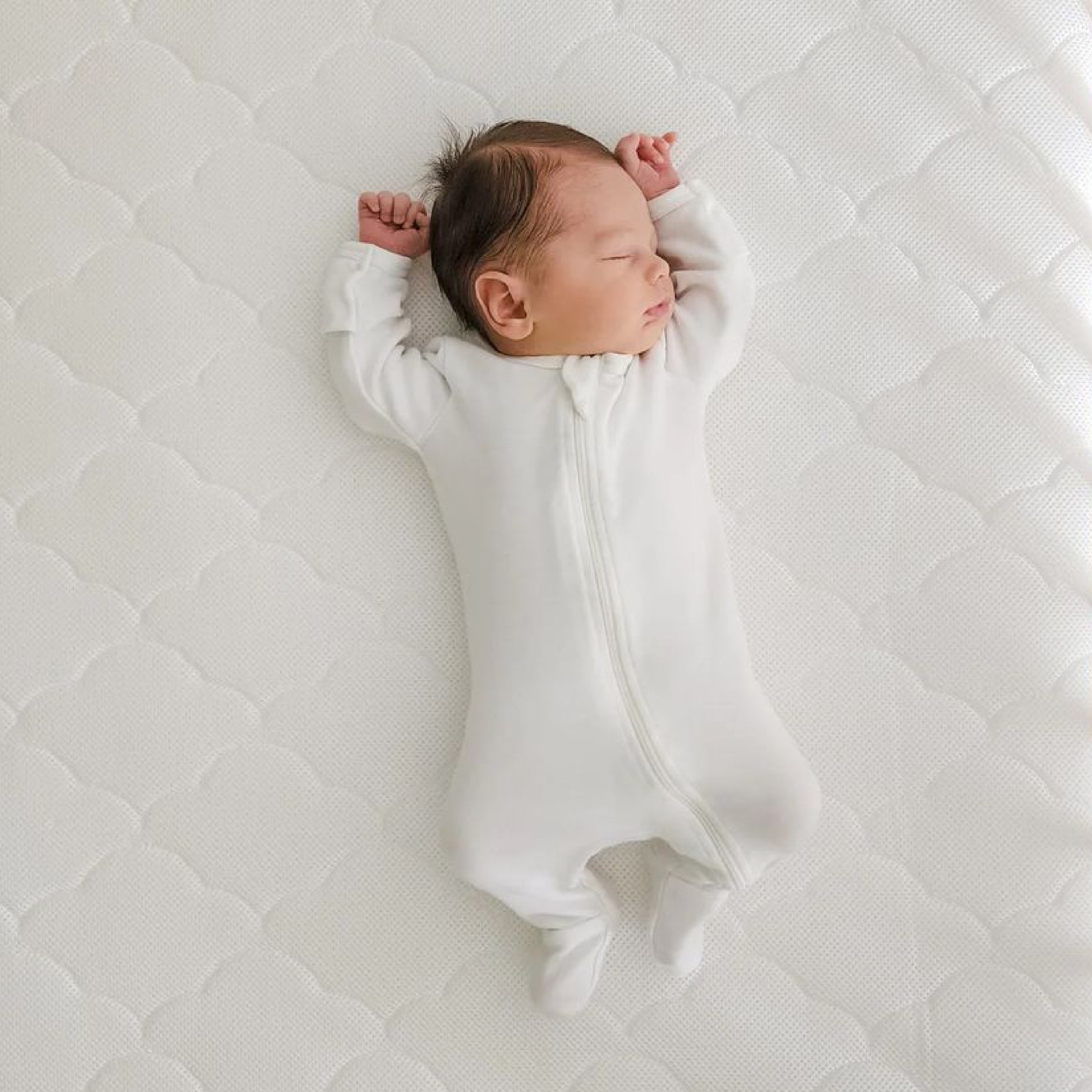 baby lying asleep on newton mattress