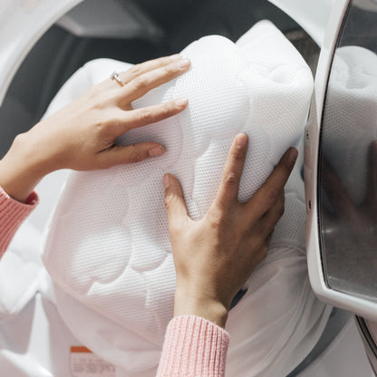 hands placing mattress cover in washing machine