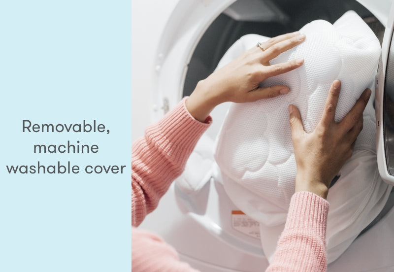 Hands placing a removable, machine washable cover into a washing machine, accompanied by text stating "Removable, machine washable cover."