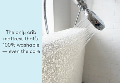 A crib mattress being washed under a shower, with text stating "The only crib mattress that’s 100% washable — even the core."