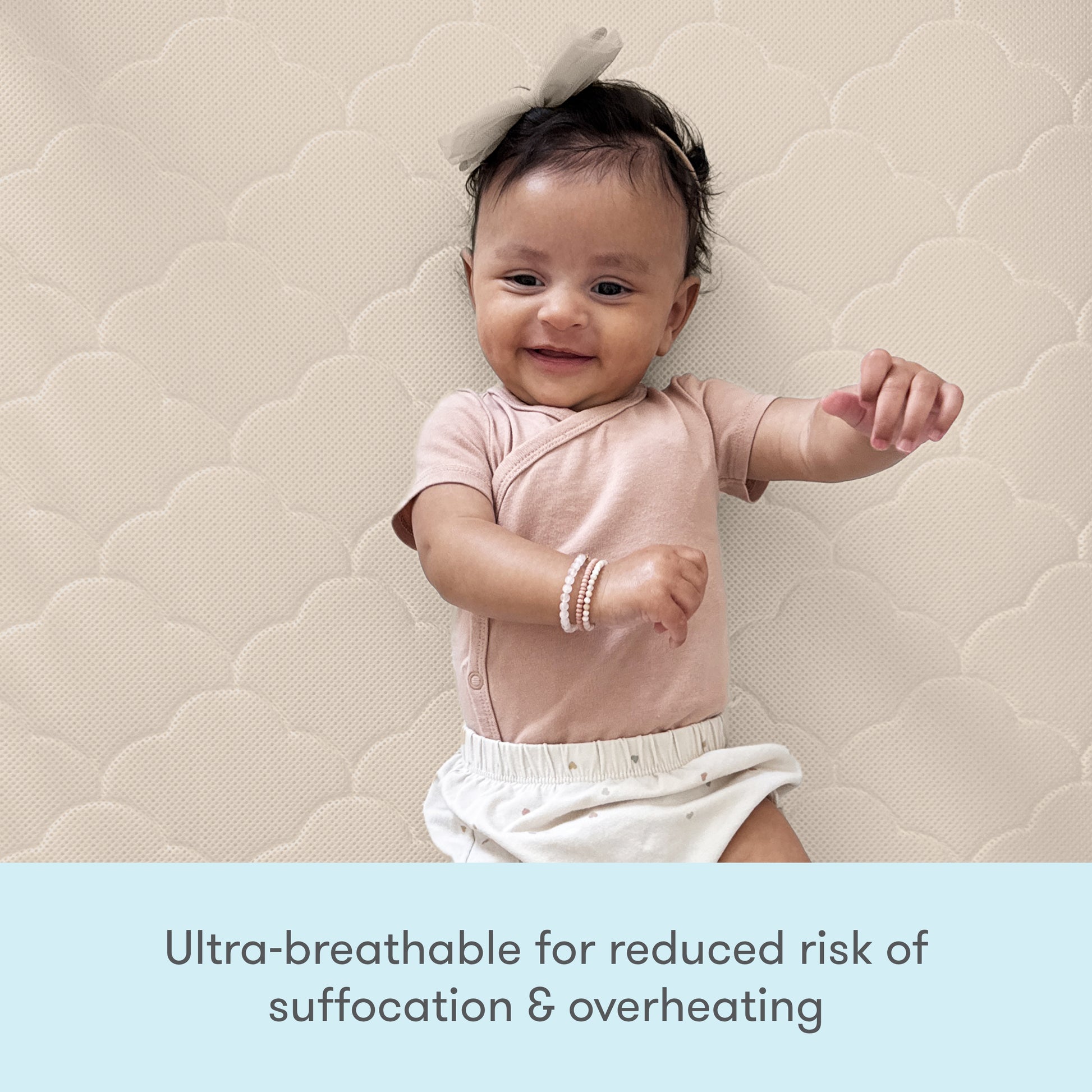 A happy baby in pink lies on a Newton Baby Crib Mattress, known for its ultra-breathable, washable design that reduces risks of suffocation and overheating.