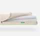 A cutaway of the Newton Baby Crib Mattress shows three ultra-breathable layers: a quilted cover, washable inner layer, and thick core—all in beige and white—with a small green label on the side.