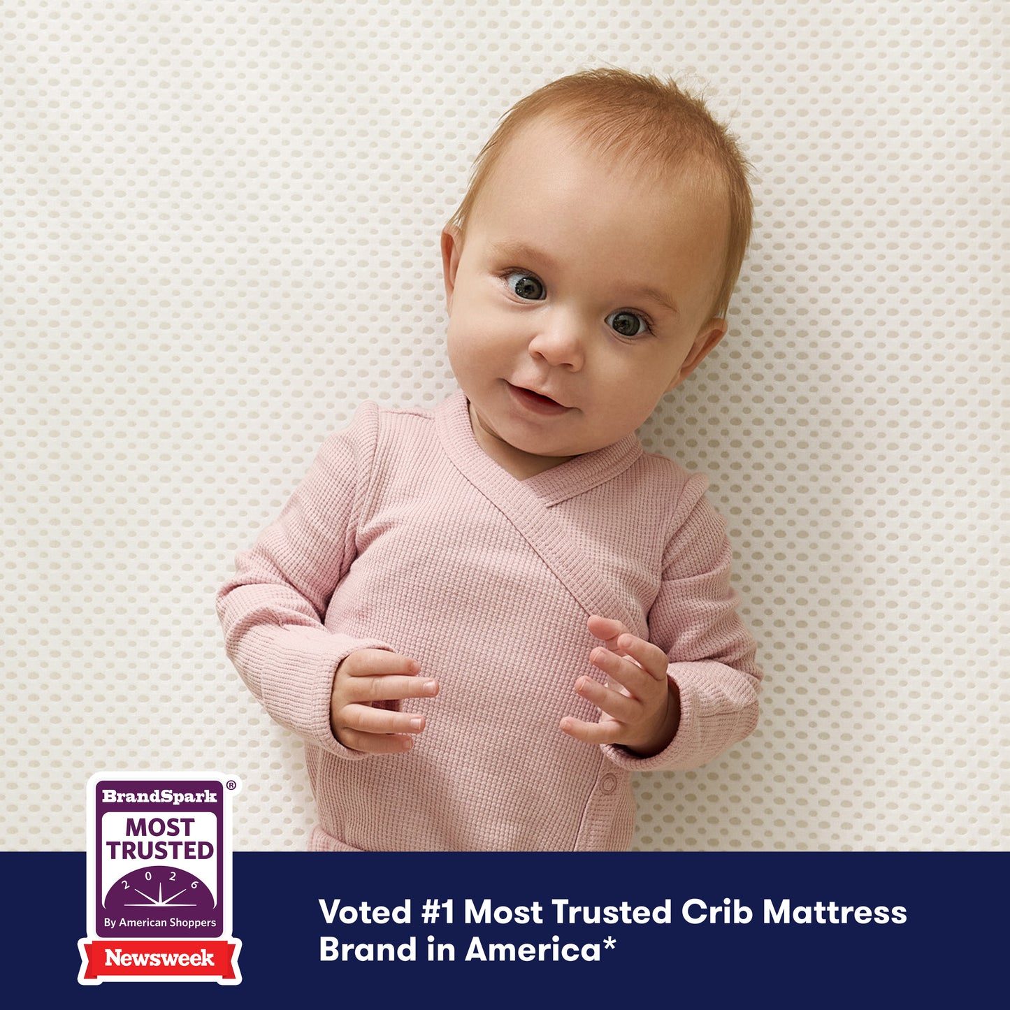A baby in pink lies on the Newton Baby Essential Crib Mattress, smiling. A bottom banner reads, Voted #1 Most Trusted Crib Mattress Brand in America with BrandSpark and Newsweek trust badges.