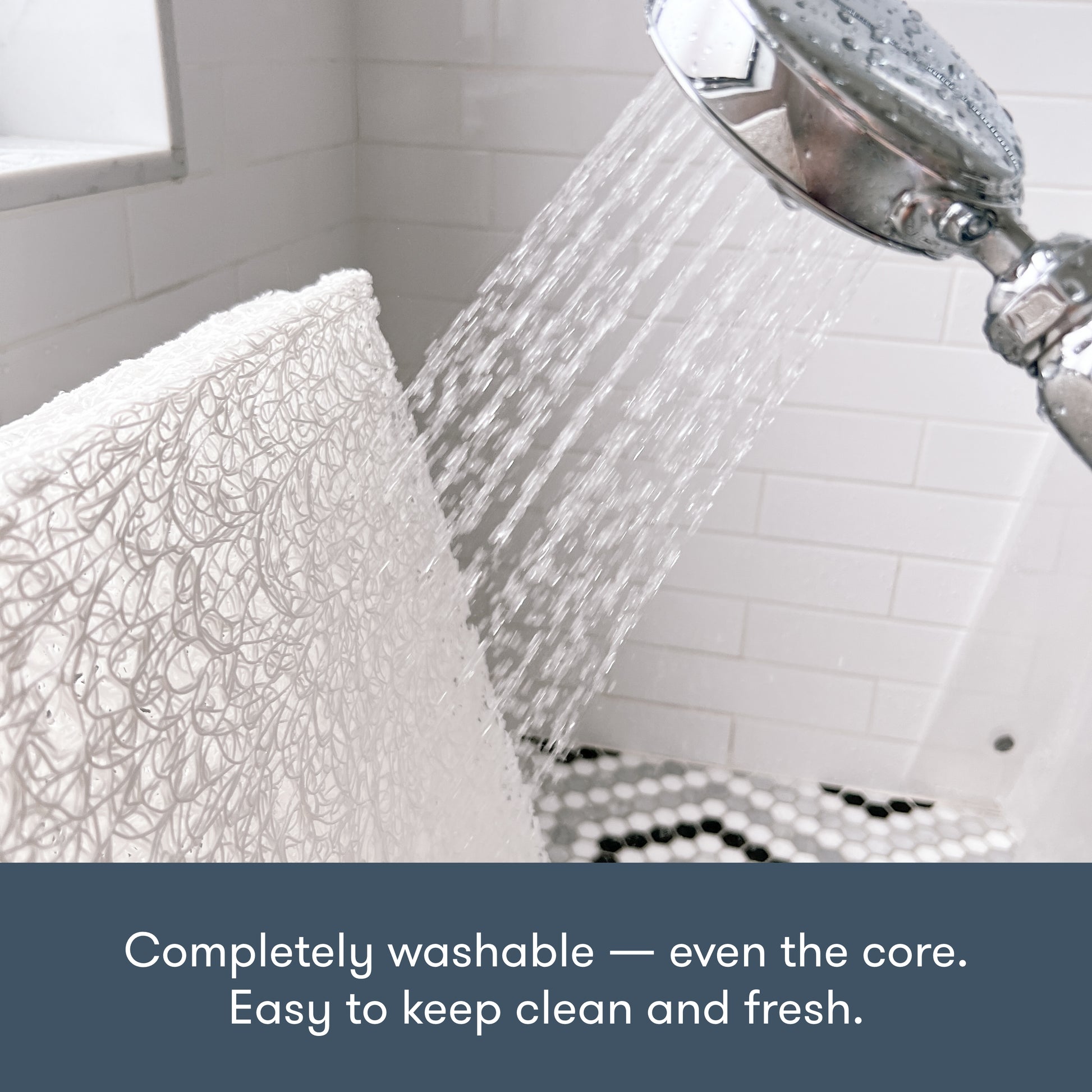 showerhead spraying water and washing down a newton pet bed core in the shower, with text "completely washable -- even the core. Easy to keep clean and fresh."