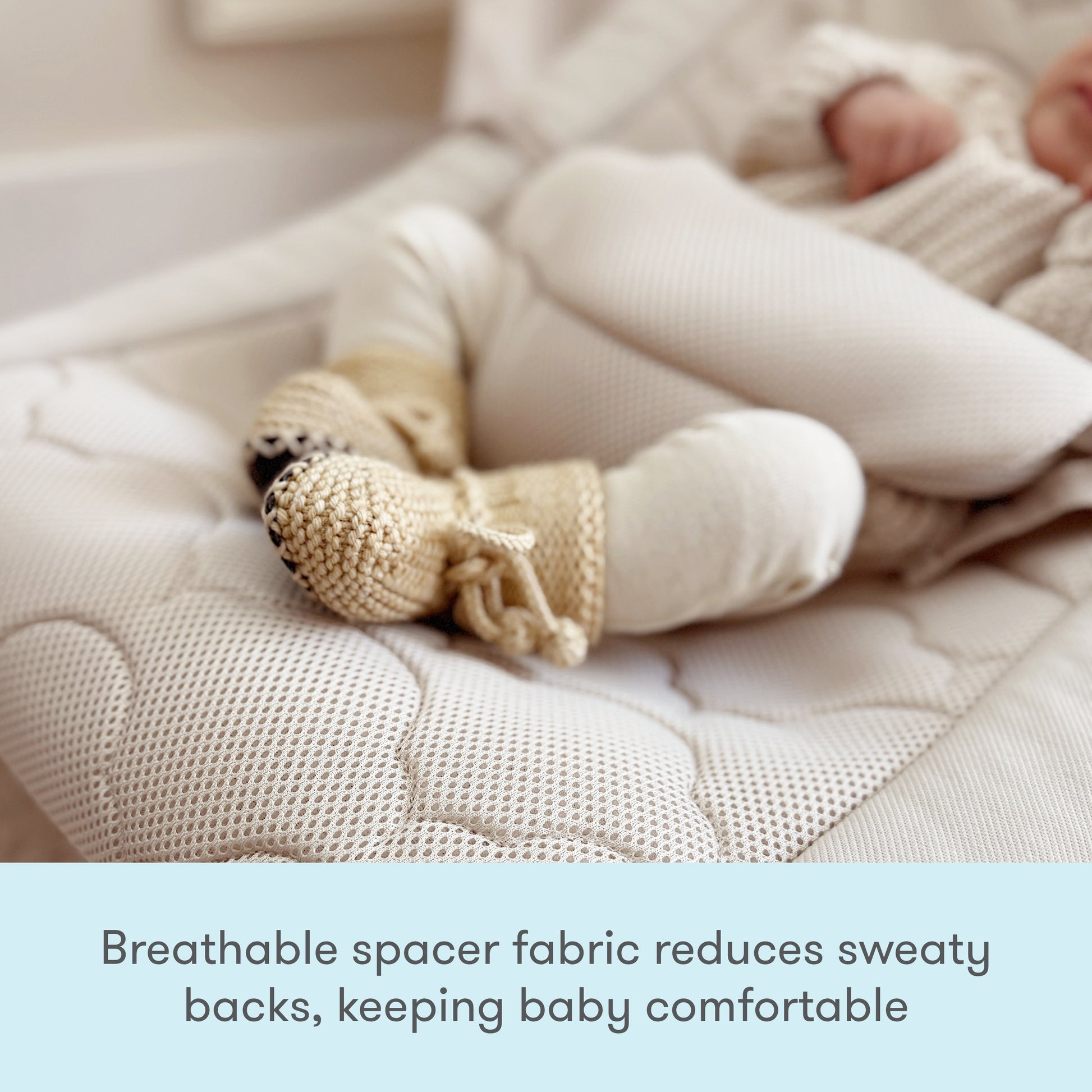 A baby in knit booties and light clothing rests on the Newton Baby Rocker’s soft, breathable quilted mattress with adjustable harness. Text reads: Breathable spacer fabric reduces sweaty backs, keeping baby comfortable.