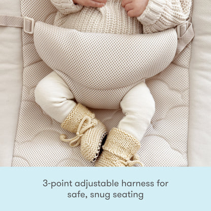 A baby wearing a knit sweater and booties sits in the Newton Baby Rocker, featuring a breathable seat cover and 3-point adjustable harness. Text below reads: 3-point adjustable harness for safe, snug seating.