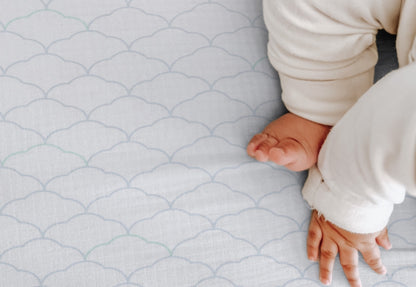 Baby's feet and hands on a soft cloud patterned sheet designed for comfortable and safe infant sleep. 999-3020-DWW 999-3520-DWW